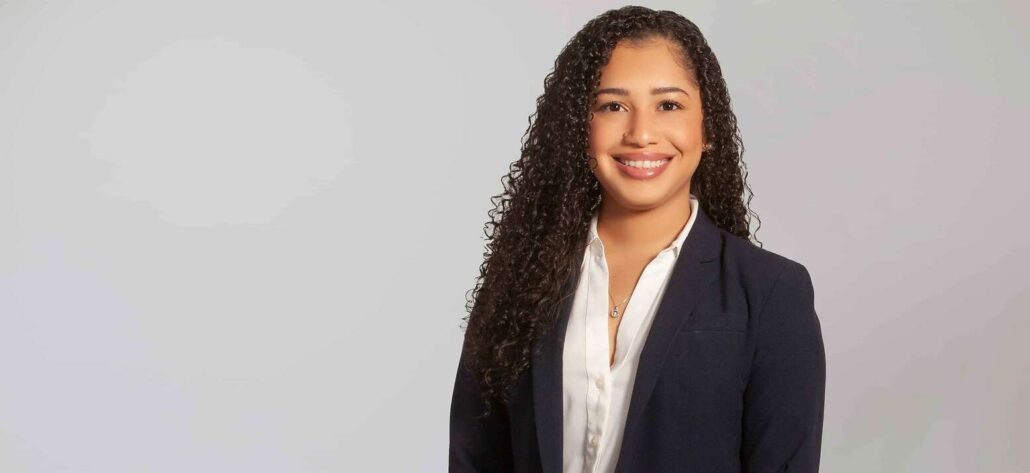 Shameka, a Black woman with black hair, wears a white shirt and black jacket.