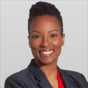 Cherell, a Black woman with black hair, wears a red blouse and black blazer, and she is smiling.