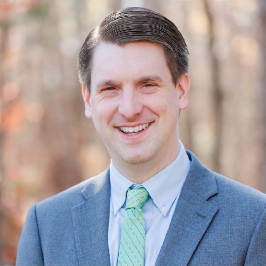 Matt, a white man with brown hair, wears a pale blue shirt, grey suit, and mint green tie.