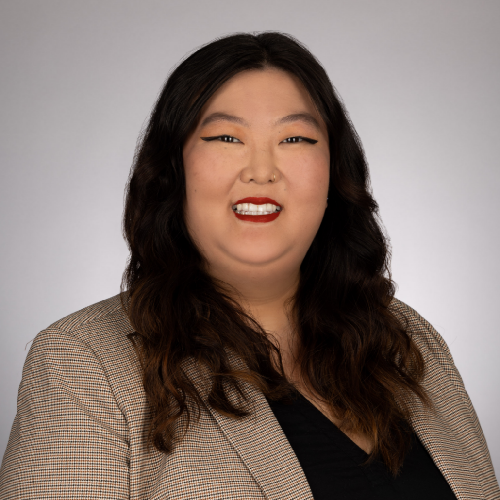 Michelle, a woman with long dark brown hair, wears a black blouse and light brown blazer.