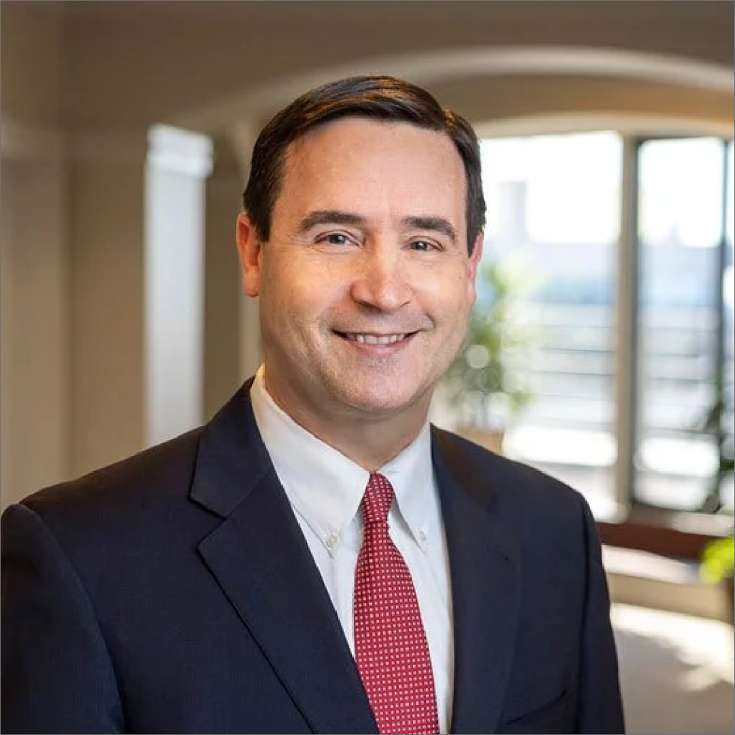 Kearns, a white man with brown hair, wears a white shirt, red tie and black jacket.