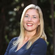 Lori, a white woman with blond hair, wears a navy blue blouse. 