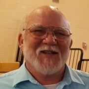 Martin, a white man with white hair and a beard, wears a pale blue button-down shirt.