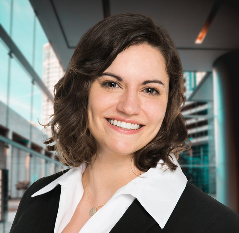 Laura, a white woman with brown hair, wears a white blouse and black blazer.
