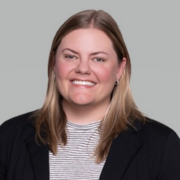 Kelley, a white woman with light brown hair and blond highlights, wears a striped white and grey blouse and a black blazer.