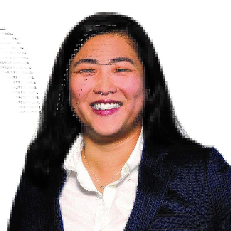 Christine, an Asian American woman with black hair, wears a white button-down shirt and black blazer.
