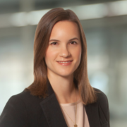 Elizabeth, a white woman with brown hair, wears a pale peach blouse and black blazer. 