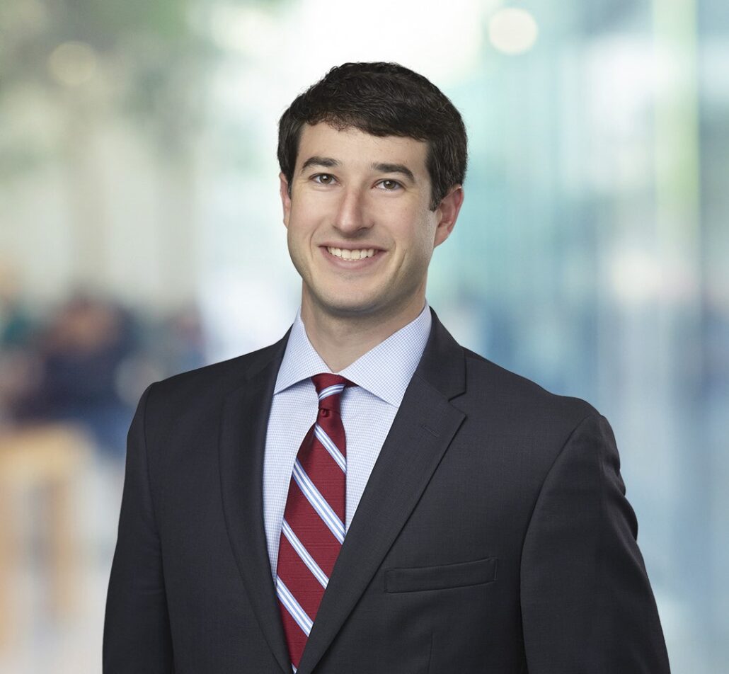 Jonathan, a white man with brown hair, wears a white shirt, red tie and black jacket.