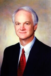 Charles, a white man with grey hair, wears a white 