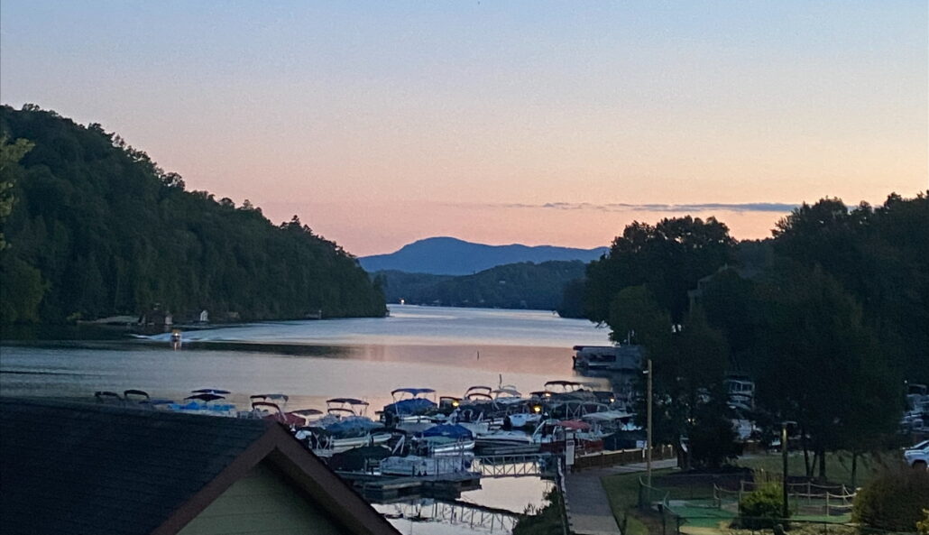 A beautiful lake is shown with boats and the sky is pink and blue.
