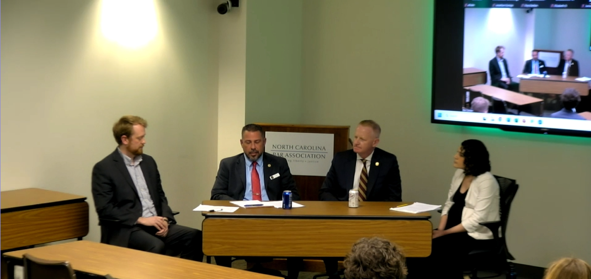 Judge Christopher Freeman and Judge Thomas Murry sit at a desk at the front of the room. Whalen and Liguori sit to the left and right and moderated the panel.