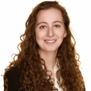 Kate, a white woman with auburn hair, wears an ivory blouse with a black blazer.