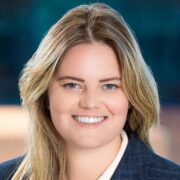 Erica, a white woman with blond hair, wears a white blouse and navy blazer.