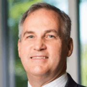 Steve, a white man with grey hair, wears a white shirt and black suit.