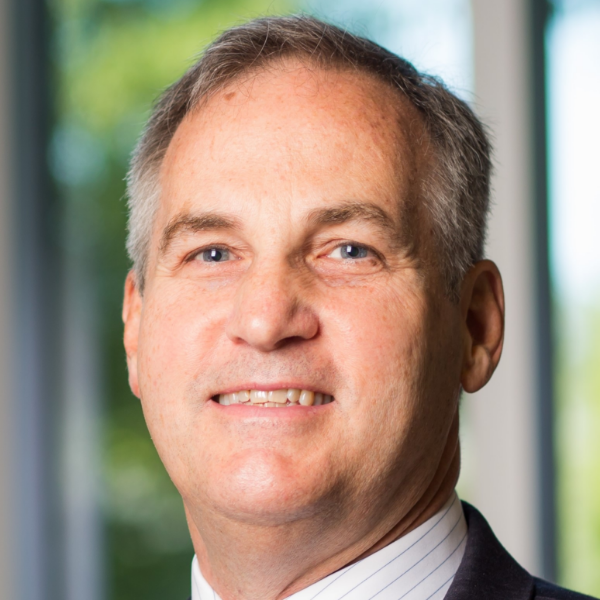 Steve, a white man with grey hair, wears a white shirt and black suit.