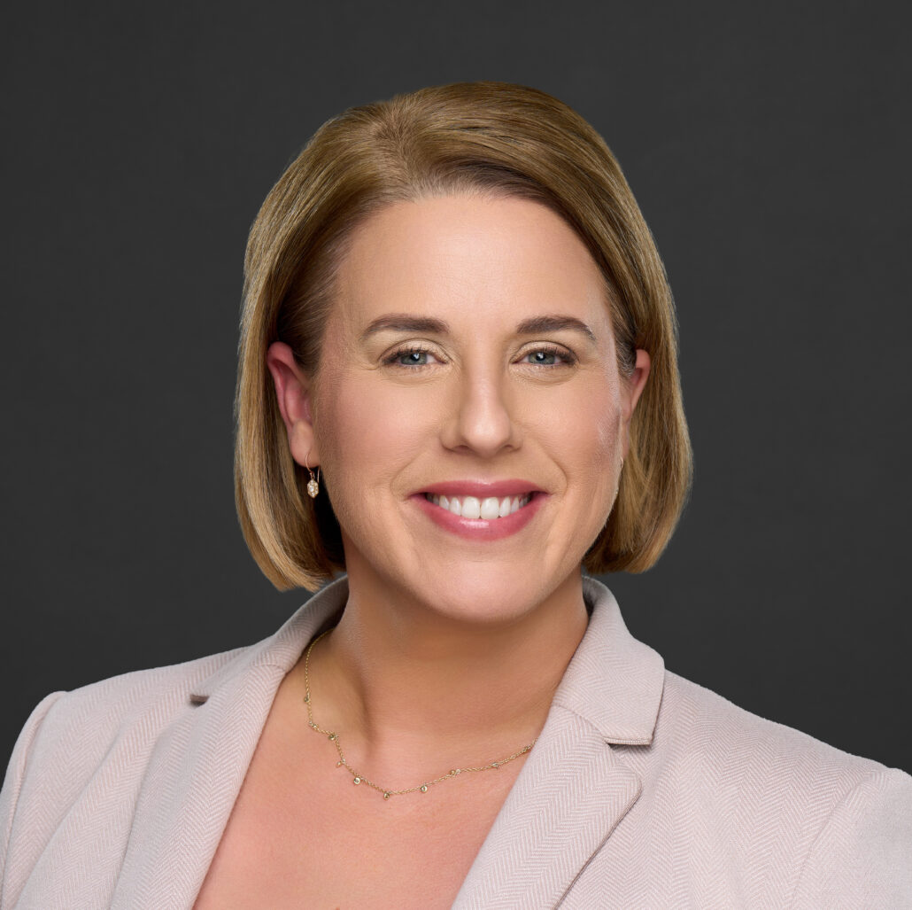 Amy, a white woman with shoulder-length blond hair, wears a black blouse and khaki jacket.