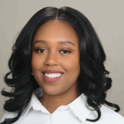 Aleah, a Black woman with black hair, wears a white blouse. 