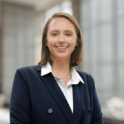Caroline, a white woman with blond hair, wears a white button down shirt and black blazer.