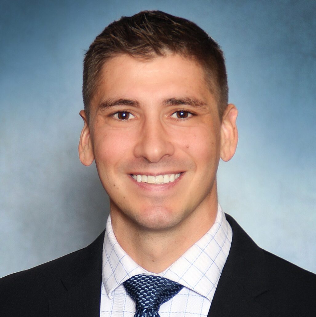Jason, a white man with brown hair, wears a white shirt, blue tie and black jacket.