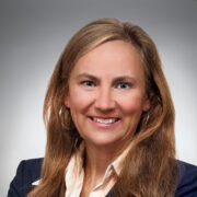 Julie, a white woman with golden brown hair, wears a white blouse and black jacket.
