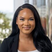 Tia, a Black woman with black hair, wears a white blousea nd black jacket.