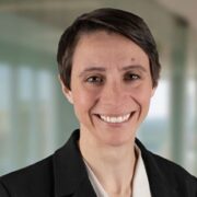 Catherine, a white woman with brown hair, wears a white blouse and black blazer.