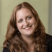 Marlo, a white woman with auburn hair, wears a black blouse. 