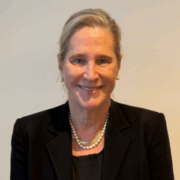 Robin, a white woman with blond hair, wears a black blouse and black blazer. 