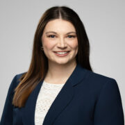 Hannah, a white woman with brown hair, wears a white blouse and a navy suit. 