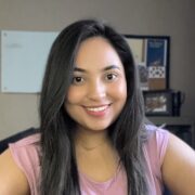 Huma, a woman with dark brown hair, wears a light pink blouse. 