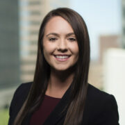 Courtney, a white woman with brown hair, wears a brown blouse and black jacket. 