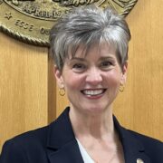 Cindy, a white woman with grey hair, wears a white blouse and black jacket. 