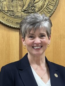 Cindy, a white woman with grey hair, wears a white blouse and black jacket.