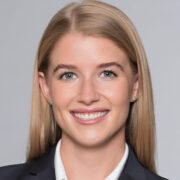 Kristin, a white woman with blond hair, wears a white blouse and black blazer.