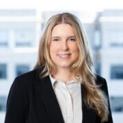 Olivia, a white woman with blond hair, wears a white blouse and black blazer.