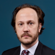 Andrew, a white man with brown hair, wears a white shirt, striped tie and black jacket.