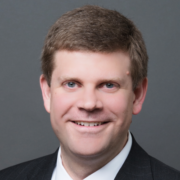 Jon, a white man with brown hair, wears a white shirt and black jacket.