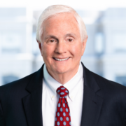 Ralph, a white man with white hair, wears a white shirt, red tie and black jacket.