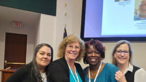 LJ, a Black woman with black curly hair, is wearing a teal blouse. She is pictured with three other CLE attendees.