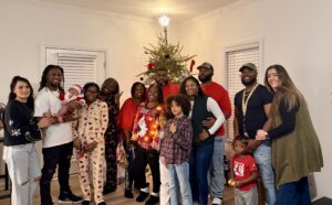 LJ is pictured with her family. They are standing in front of a Christmas tree. 