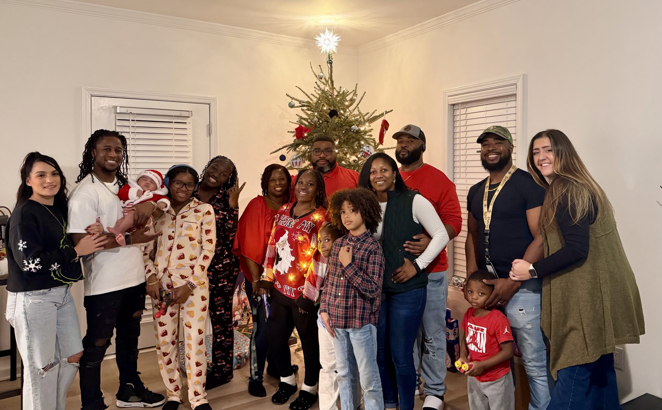 LJ is pictured with her family. They are standing in front of a Christmas tree.