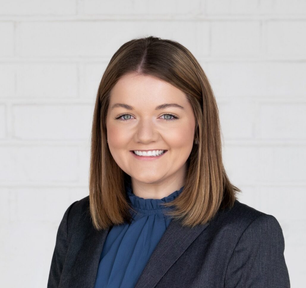 Kasey, a white woman with shoulder length brown hair, weras a blue blouse and black jacket.