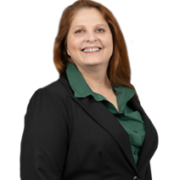 Andrea, a white woman with auburn hair, wears a green blouse and black blazer.