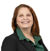 Andrea, a white woman with auburn hair, wears a green blouse and black blazer.