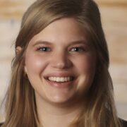 Christiana, a white woman with blond hair, wears a black blouse.