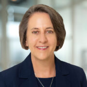 Terrill, a white woman with brown hair, wears a black blouse and black jacket. 