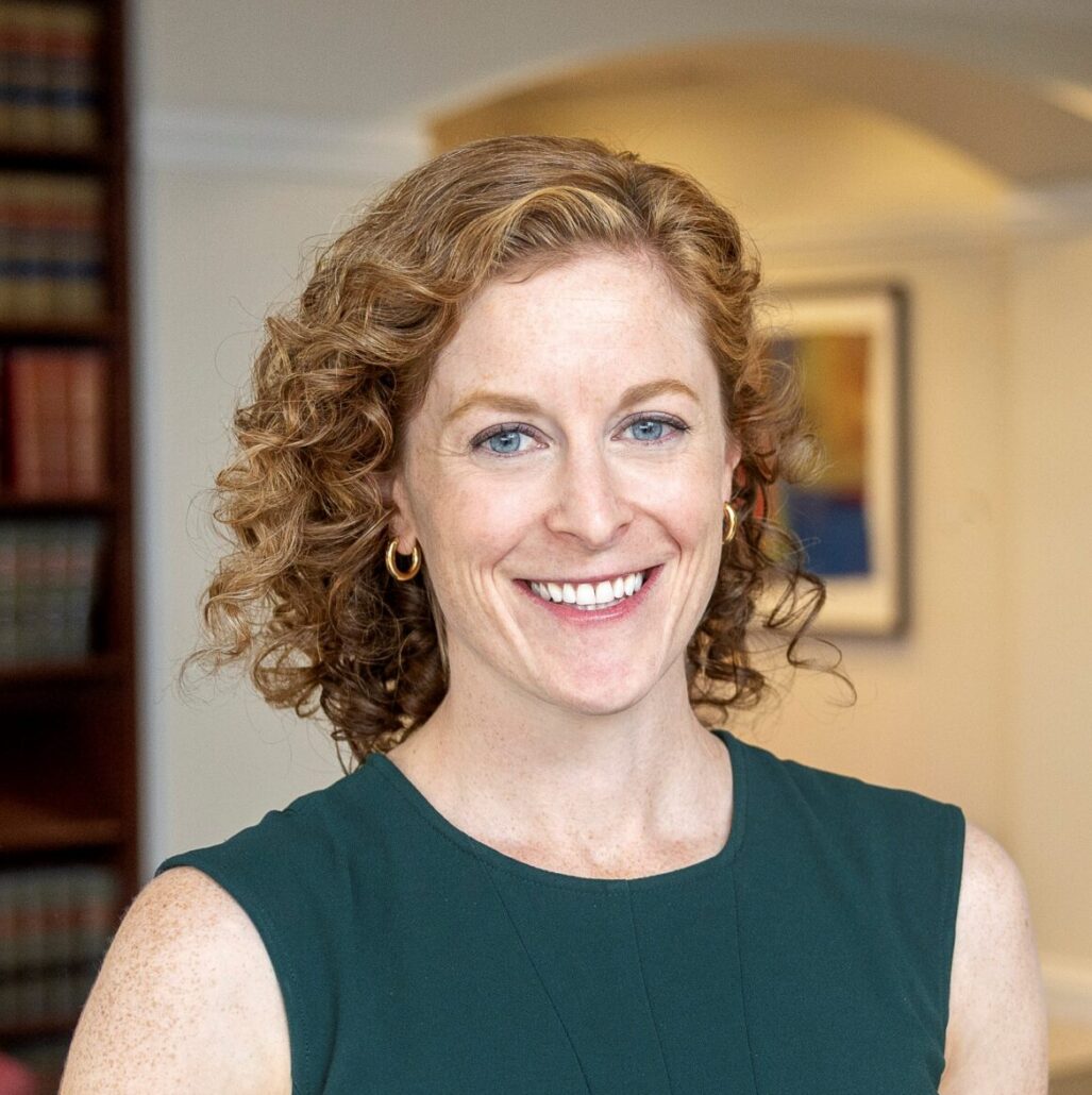 Claire, a white woman with curly blond hair, wears a green sleeveless dress.