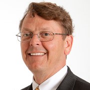 Keith, a white man with brown hair, wears wire-rimmed glasses, a white shirt and black jacket.