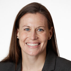 Allison, a woman with brown hair, wears a white blouse and black suit.