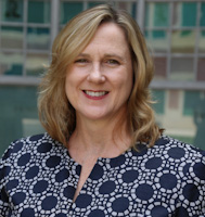 Amber, a white woman with golden brown hair wears a blue and white blouse.